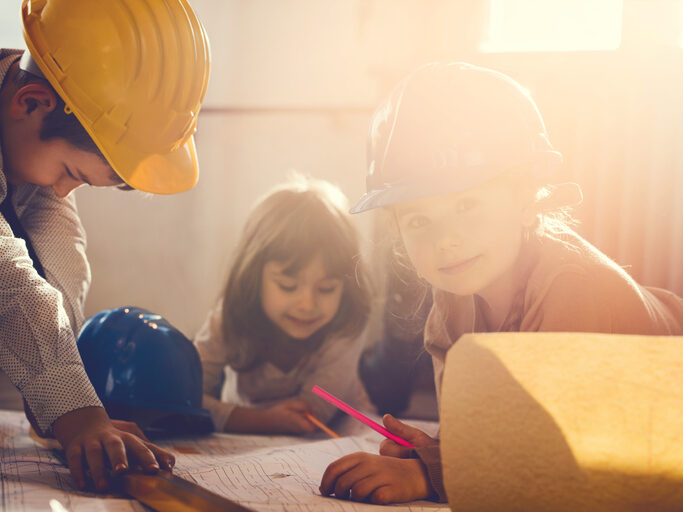 Two little girls and little boy architects writing blueprint.